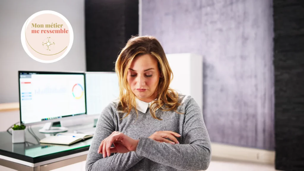 Une femme au bureau regarde sa montre, pressée de rentrer, signe pour elle qu'il est temps de changer de travail
